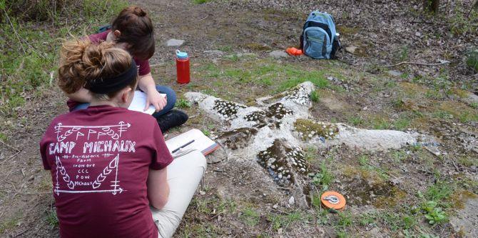 Students recording details about an artifact in the shape of a star 