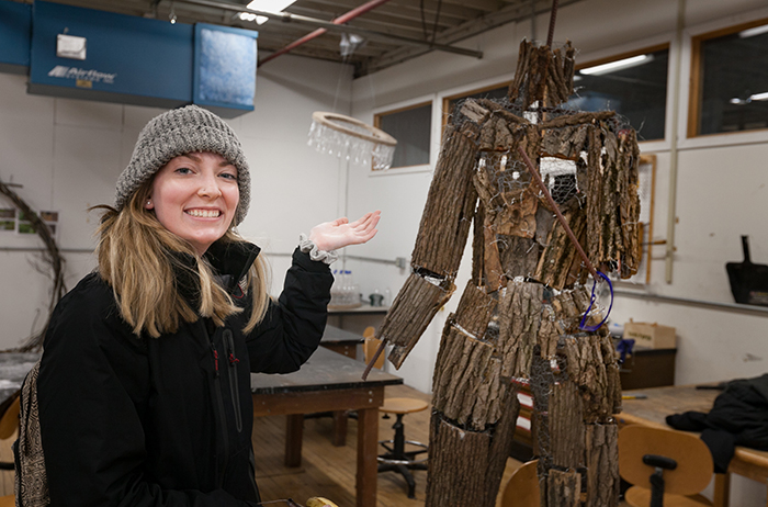 A student creates a sculpture out of natural materials for a juried outdoor exhibition.
