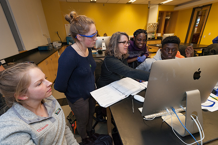 Students work together in front of a computer in a biology lab.