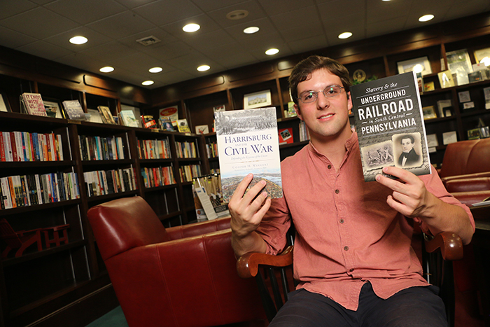 cooper wingert holds up two of his most recent books.