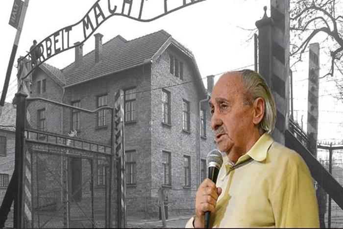 David Tuck stands in front of a picture of a Nazi concentration camp.