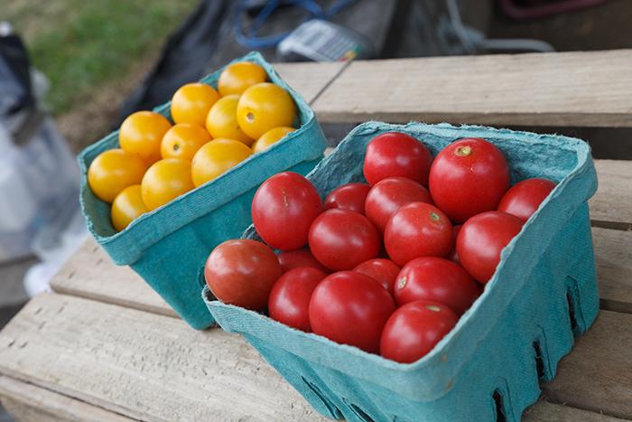 Two packages of cherry tomatoes sitting on a wooden table.