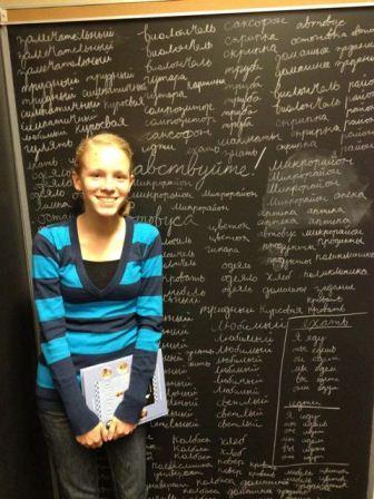 A picture of a girl standing next to a chalk board.