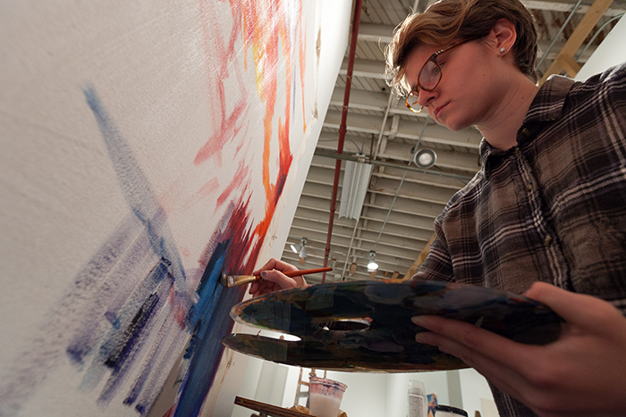 Sammy Holden '18 (art & art history, political science) works on a new painting in the Goodyear Gallery.