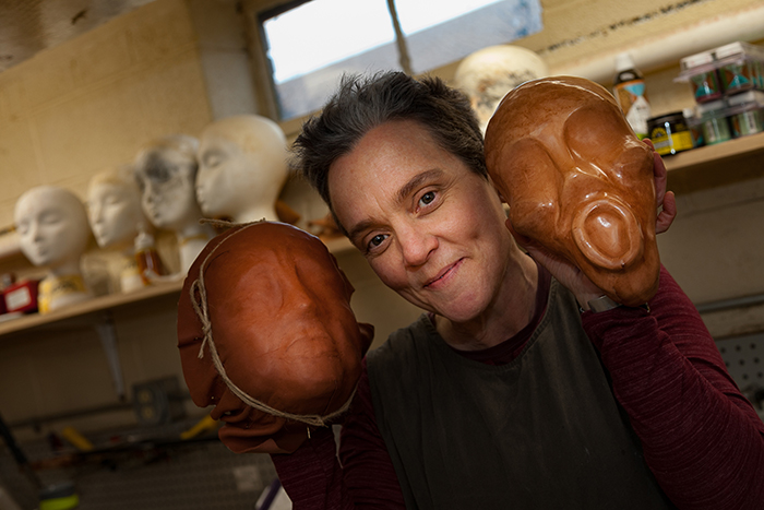Professor of Theatre Sherry Harper-McCombs poses with masks-in-progress during a sabbatical focused on maskmaking and puppetry. Photo by Carl Socolow '77.
