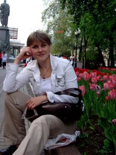 On-site Dickinson-in-Moscow director Irina Filippova, sits in front of a flower bed.