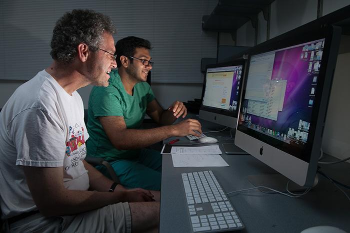 Associate Professor of Computer Science Timothy Wahls and Asir Saeed '16, their faces illuminated by their computer screens, clean up water quality data. Photo by Carl Socolow '77.