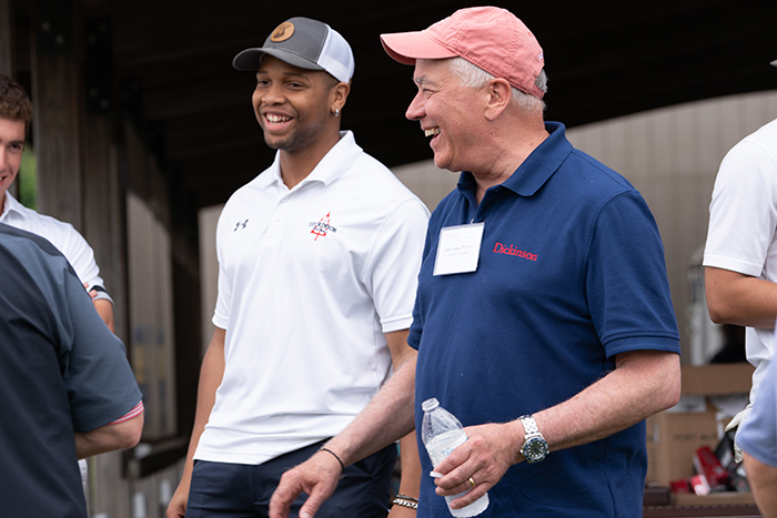 Dickinson&#039;s incoming interim president, John Jones III, a member of the class of 1977, attended the McAndrews Golf Tournament. Here he chats with Bryce Baylor '22, a Red Devils running back. Photo by Dan Loh.