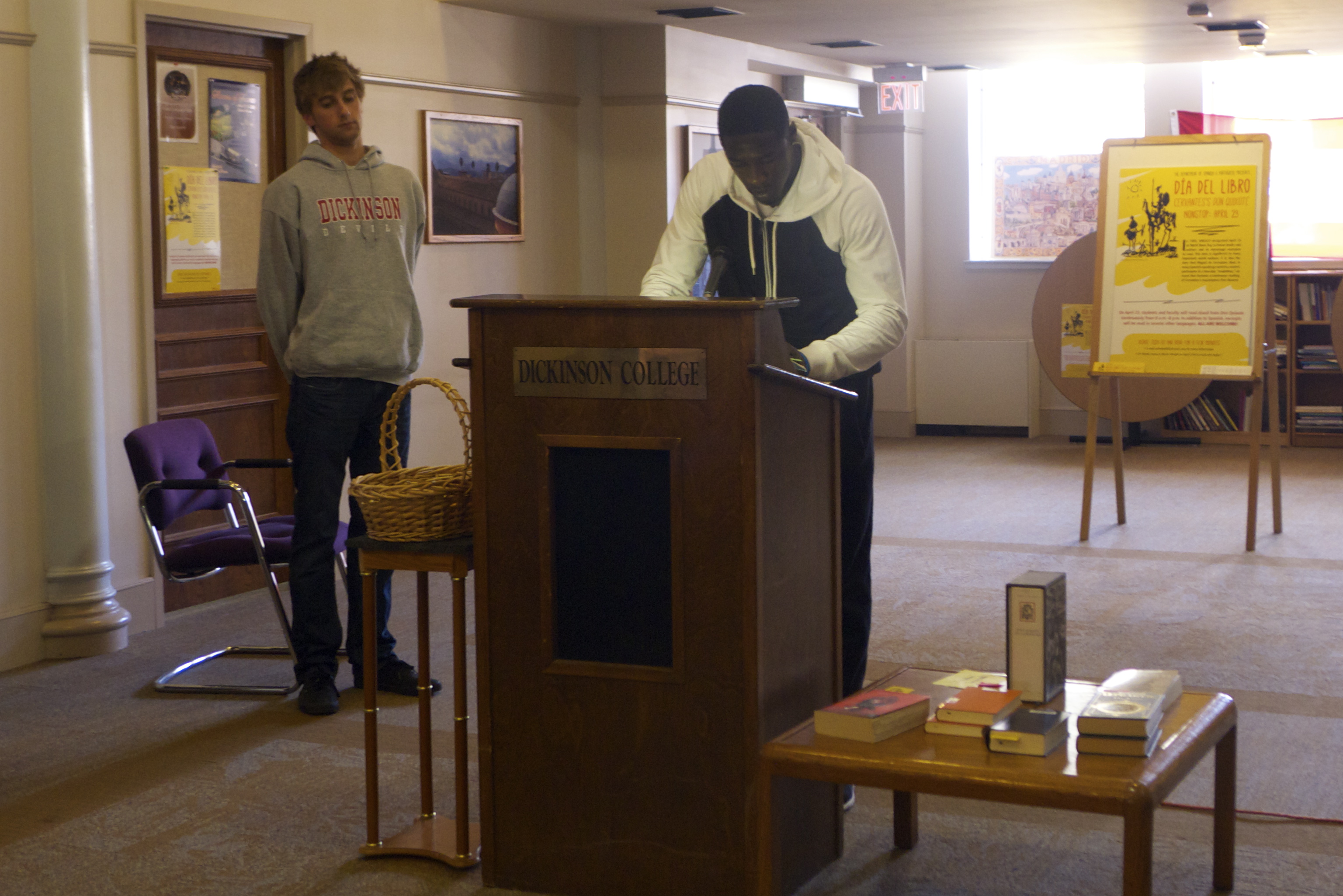 A student reads from Don Quixote in the Biblio Café while another student stands by for his turn at the podium. 
