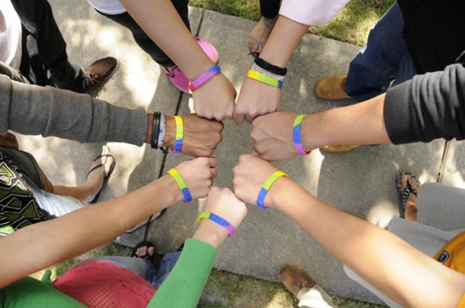 Hands in a circle showing pride bands.