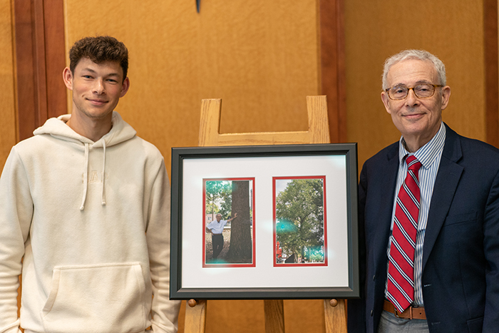 Weissman and grandson Matthew Presite '23 pose before a photo of a tree that was planted during Weissman's first year at Dickinson. Like Weissman's legacy, it has grown exponentially. Photo by Dan Loh.
