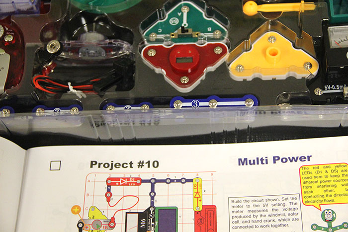 An instruction manual is opened to project number ten, guiding curious learners of all ages to make their own circuits.