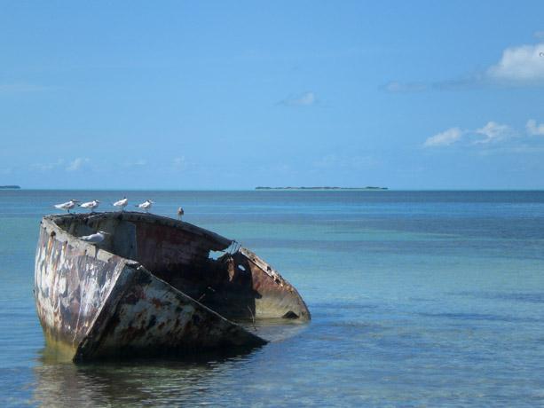 A boat resting in the water off of a Caribbean island.