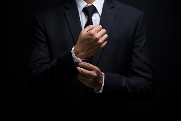 Photo of a man in a business suit adjusting his cufflinks.