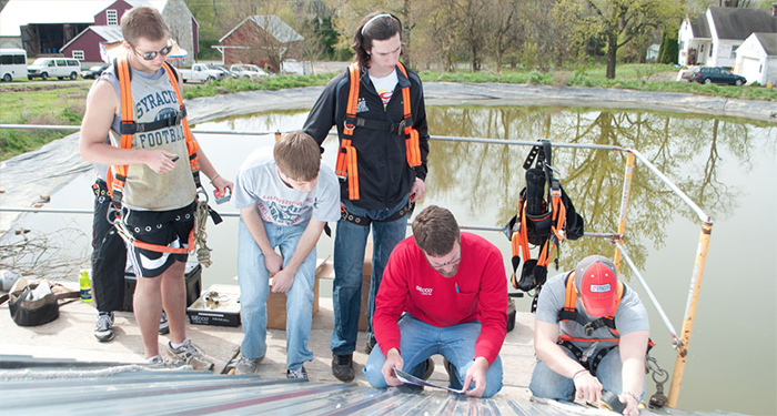 Students install solar panels on the roof of the Dickinson College Farm pump house.