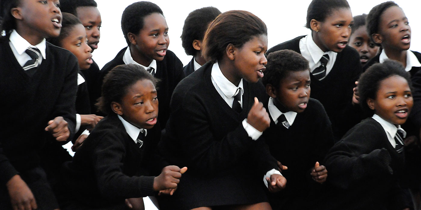 South African girls in school uniforms dancing and singing.