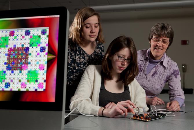 Three female scientists test out a computer science project.