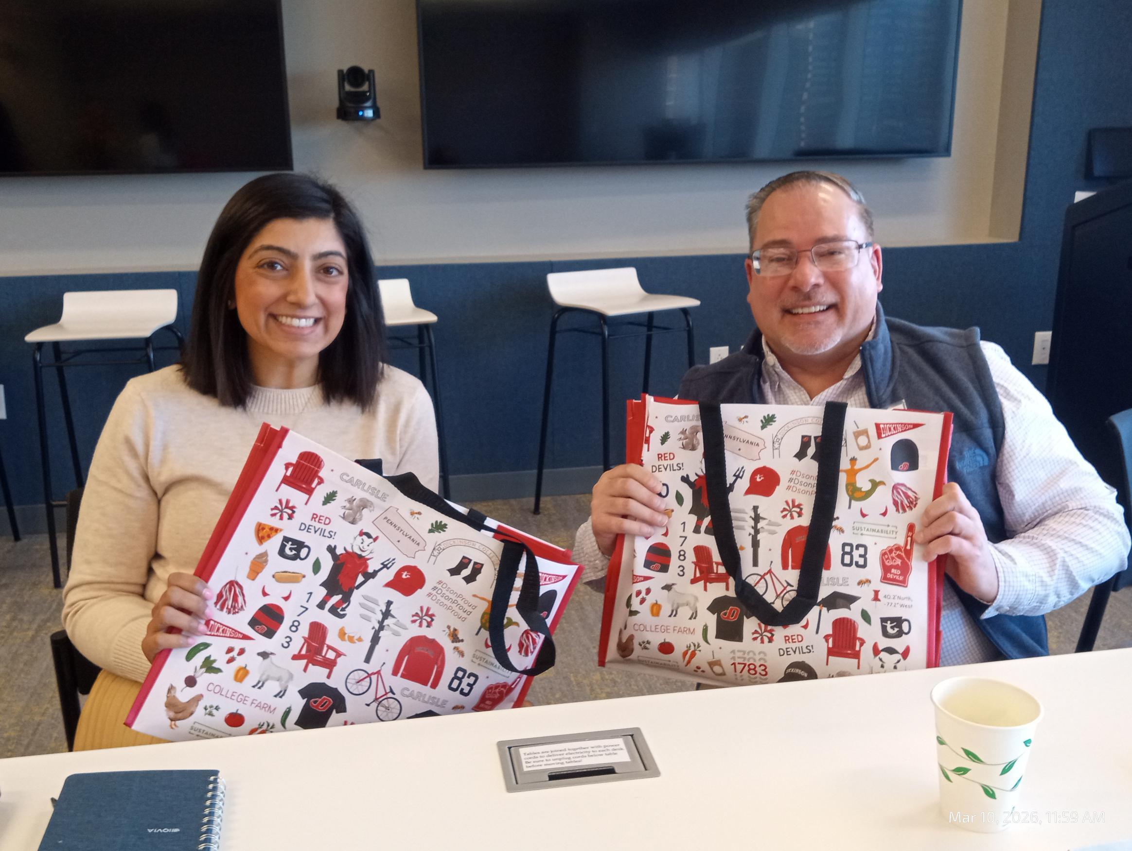 Two alumni holding Dickinson College gift bags 