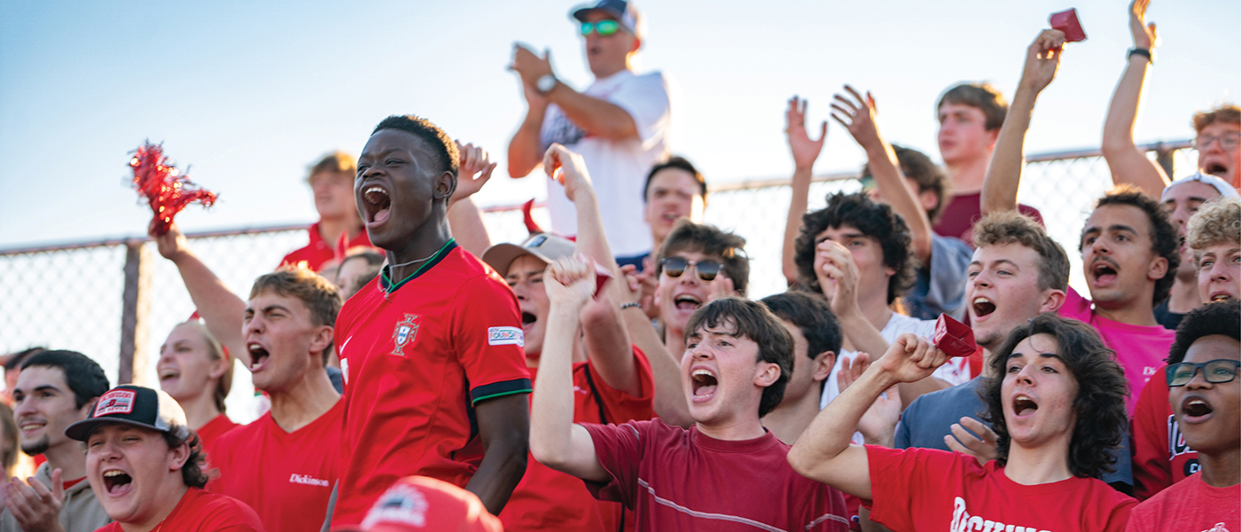 A group of students cheering at a Dickinson sporting event