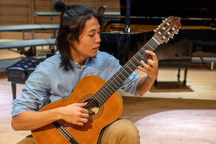 student performing on the guitar.