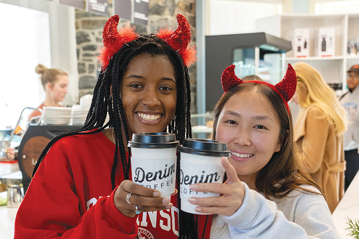 Two Dickinson students pose with Denim Coffee cups and devil horn headbands