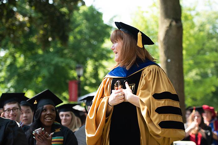 Amy McKiernan looks excited and astonished as she walks among graduates to accept an award at Commencement.