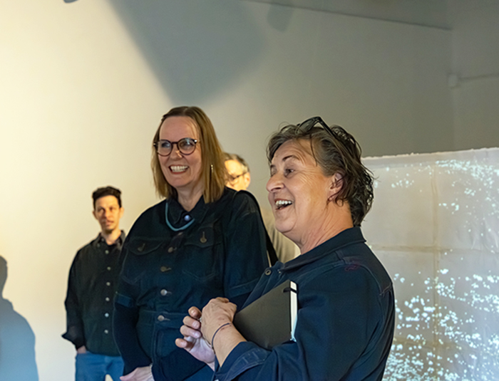 two women smiling in a gallery.