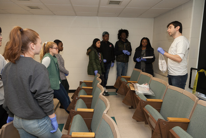 Students examine a staged crime scene to explore a wide array of scientific fields