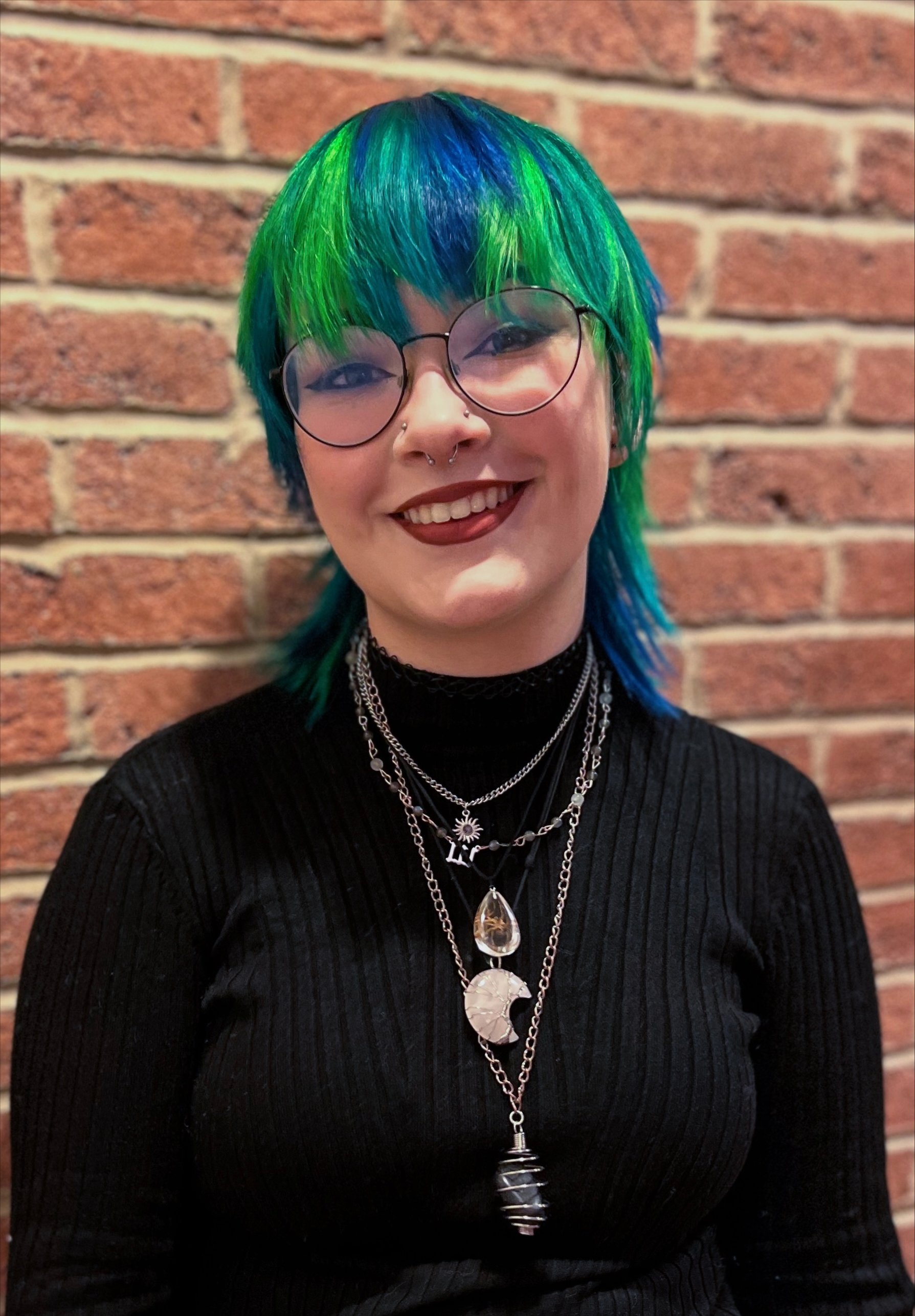 A person with green and blue hair and a black top