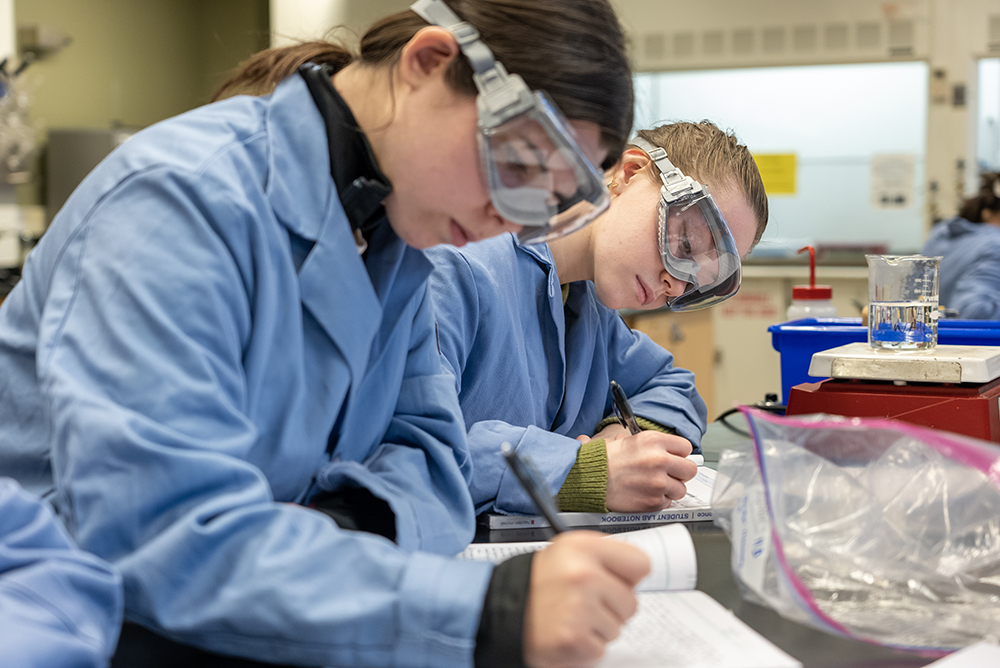 Two students in protective clothing work in the Dickinson chemistry lab
