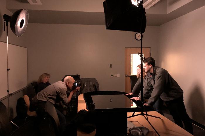 A photo of a photographer taking a picture of two Dickinson students inside a classroom.