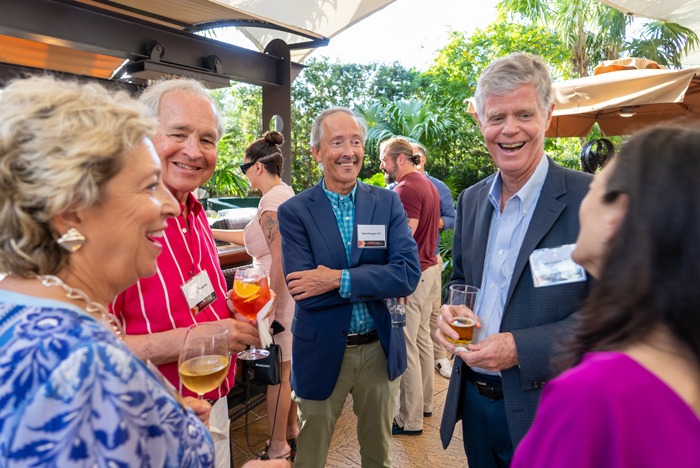 Mark Burgess '81 welcomes guests to the Miami event, including Jennifer Ward Reynolds '77 and her husband, George (left) and Tom Logue '77 (right).