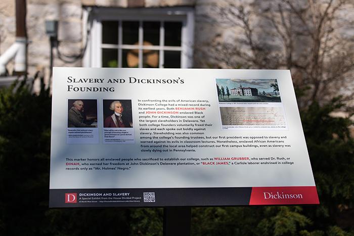 Photo of Dickinson & Slavery sign in the shade of tree branches.