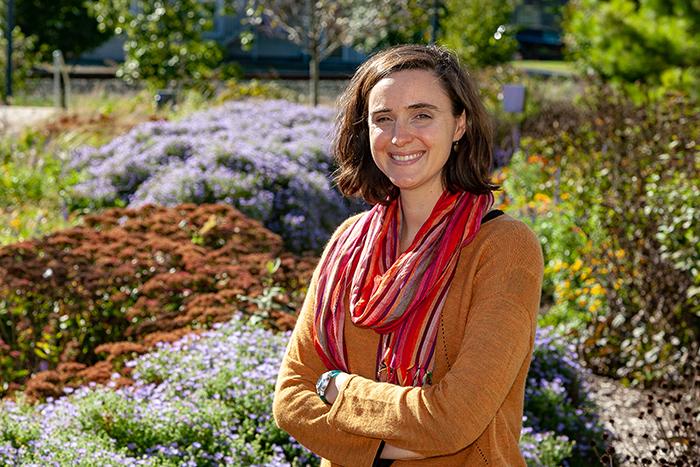 Portrait of a woman standing in front of a garden.