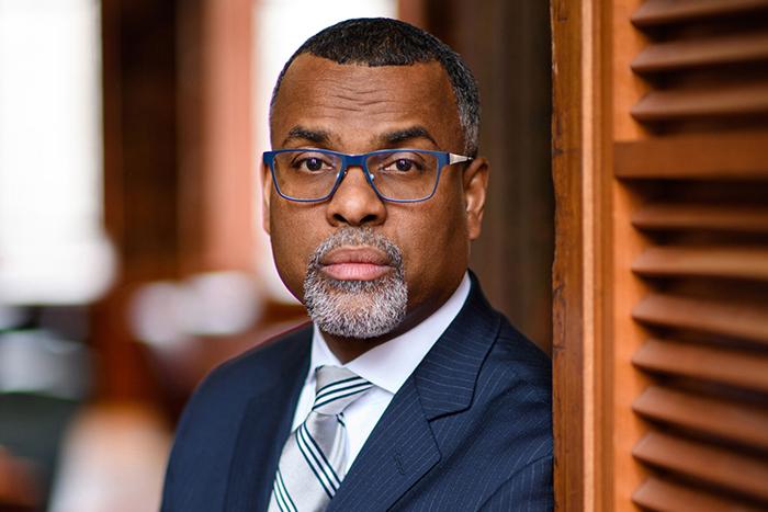 Portrait of Eddie Glaude, Jr., leaning on a wooden door.