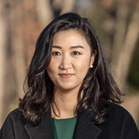 Portrait of Eunji Kim standing in front of trees.