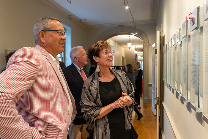 Honorees Doug '80 (far left) and Terri Pauls read a plaque hung in their honor as President John E. Jones III '77, P'11 looks on. Photo by Dan Loh.