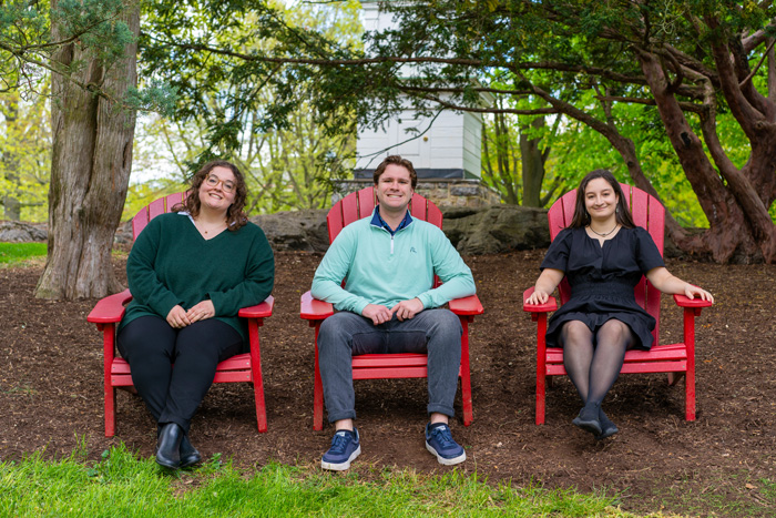 three students pose in red chairs