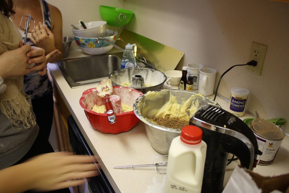 Two bundt pans being filled with cake batter.