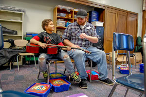 student teaching kid to play guitar 