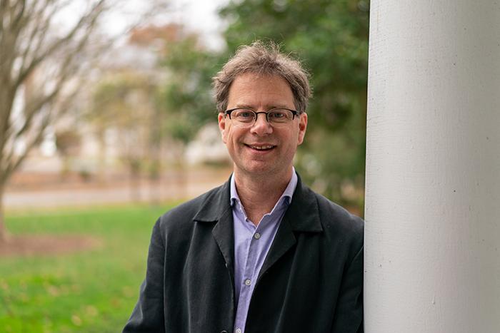 Photo of John MacCormick leaning against a column outdoors.