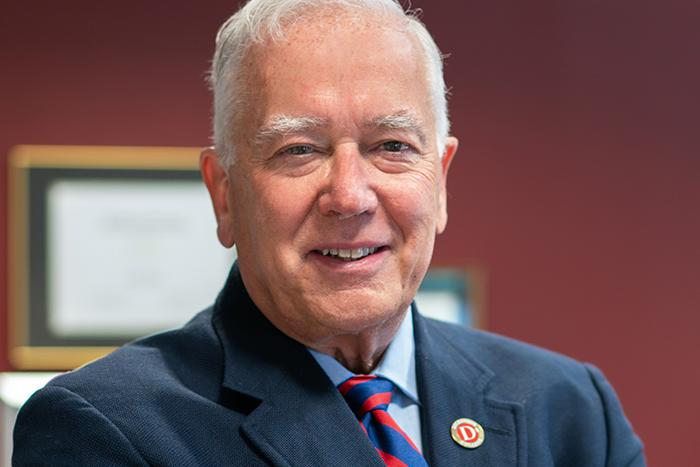 Portrait of a man standing in front of a red wall.
