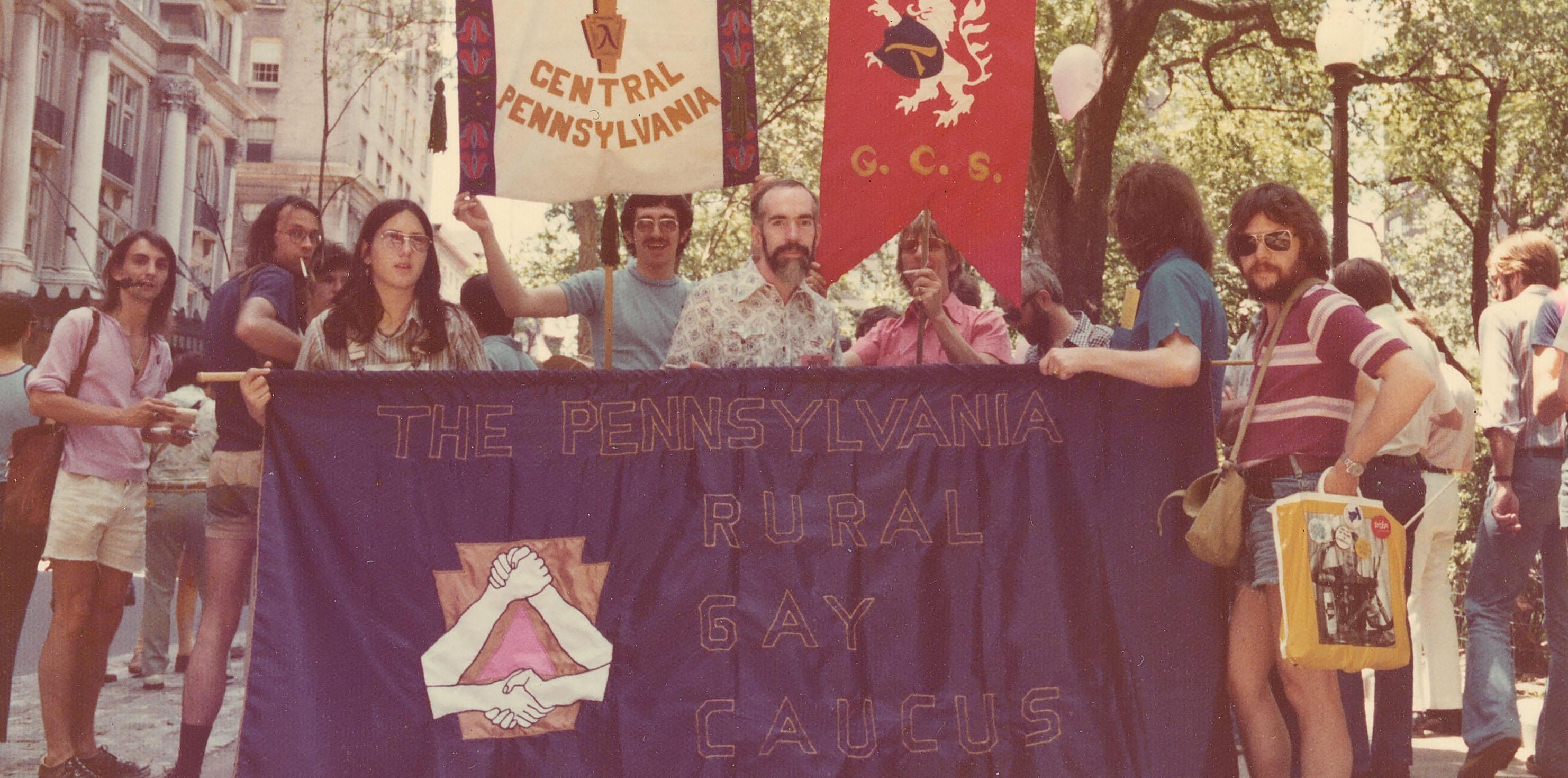 Philadelphia Pride parade attendees pose with a  "Pennsylvania Rural Gay Caucus" banner.