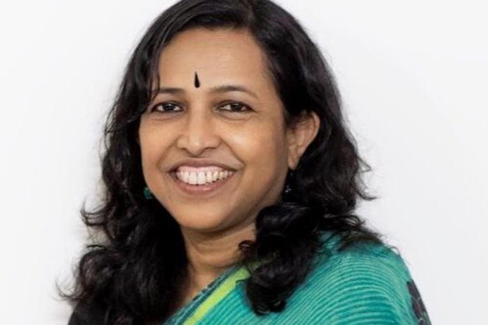 Portrait of Malabika Sarker. Woman in front of a white background wearing a blue-green top.