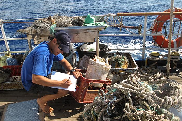 Nick Mallos ’07 combs through a ghost net. These lost or abandoned fishing nets can accumulate several thousand pounds of debris.