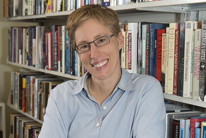 Portrait of Margot Canaday standing in front of a bookshelf.