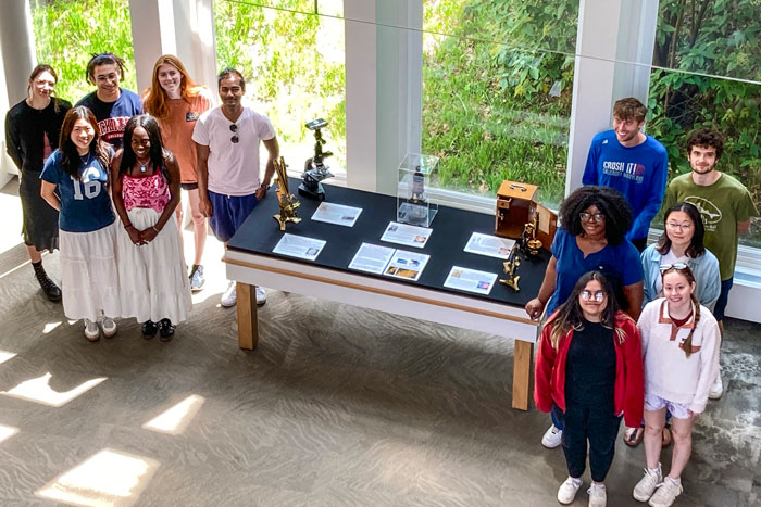 students gather in front of historic microscopes