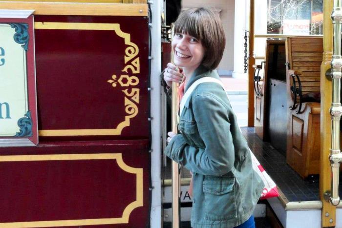 Miriam Weiner latching on to a pole that appears to be a part of a trolley.