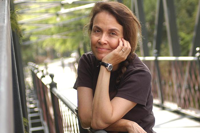 Photograph of Naomi Shihab Nye standing on a bridge.