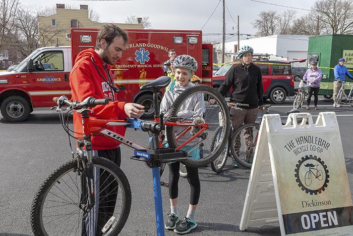 Photo of a college student and a child with a bicycle standing in a parking lot.